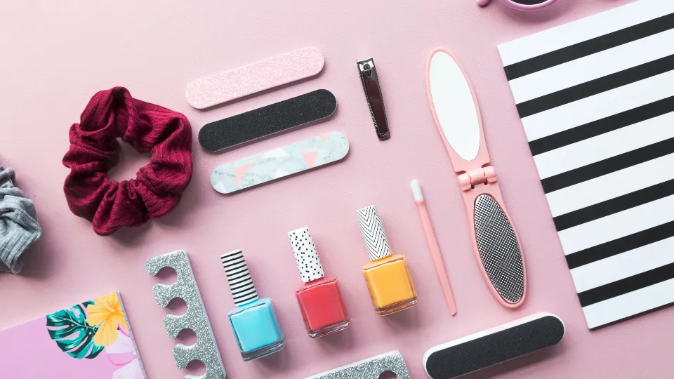 Flesjes nagellak en verzorgingsspulletjes op een roze ondergrond