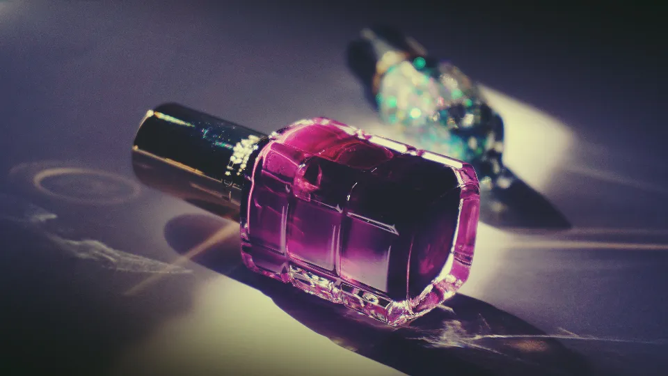 Paarse nagellak in een glazen flesje met licht erachter