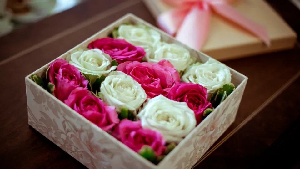 Cadeaudoos met roze en witte rozen op een houten tafel