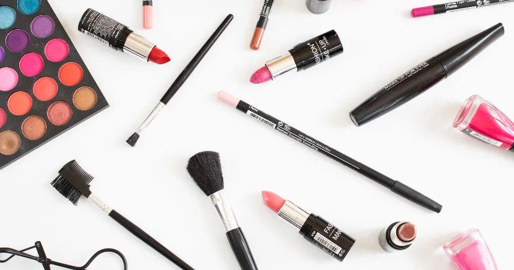 Lippenstiften, kwasten en een oogschaduwpalet op een witte ondergrond